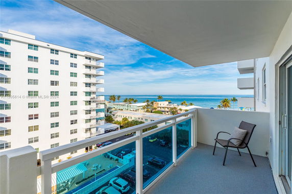 View from a balcony overlooking the ocean and a nearby apartment building.