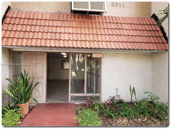 Front view of a building entrance with a red tiled roof and glass door.