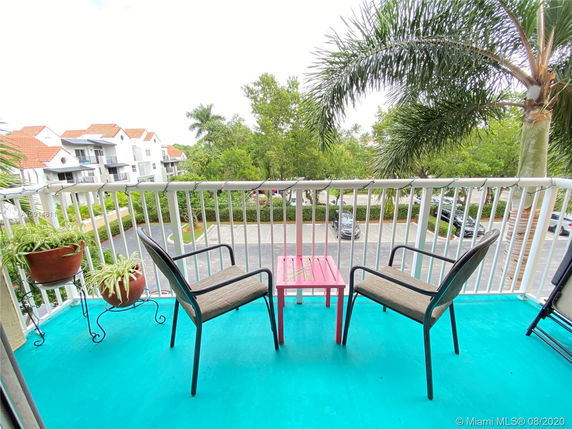 Balcony with chairs overlooking a parking area and nearby buildings.