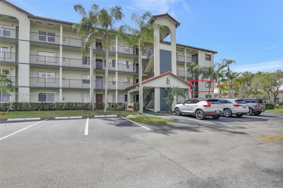 Front view of a four-story apartment building with parking area.