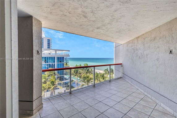 View from a balcony overlooking the ocean and nearby buildings.