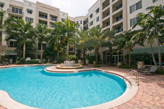 View of a swimming pool with a multi-story residential building in the background.
