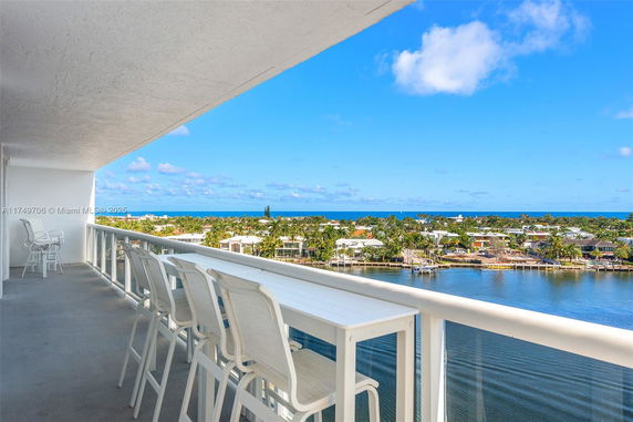 Panoramic view from a high-rise balcony overlooking water and distant buildings.