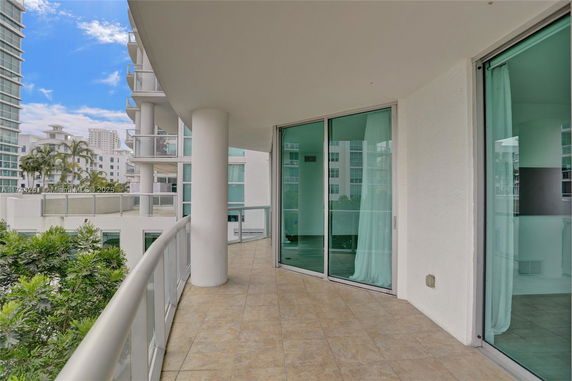 Balcony view with glass railings overlooking nearby buildings