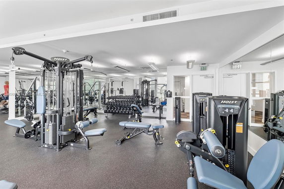 Room with various gym equipment and mirrors