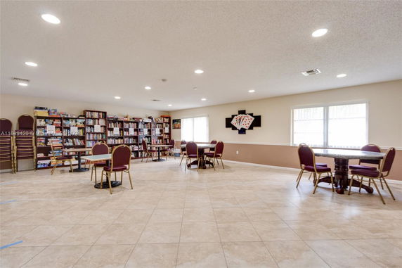 Interior view of a recreational room with bookshelves and card tables.