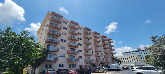 Front view of a multi-story apartment building with balconies on each level.