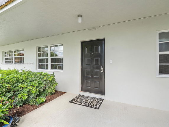 Front view of a building with a black door and white windows.