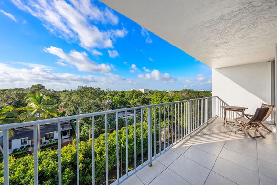 View from a balcony looking over lush green surroundings and distant cityscape.