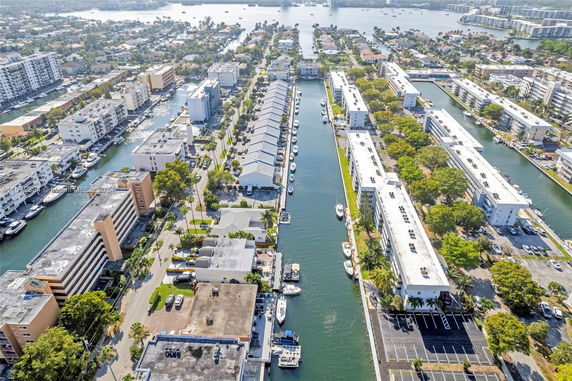 Aerial view of a canal with buildings lining both sides, featuring multiple boats docked along the waterway.