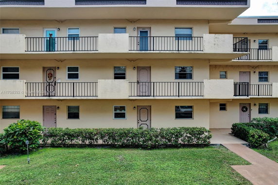 Front view of a multi-story building with balconies and doors.