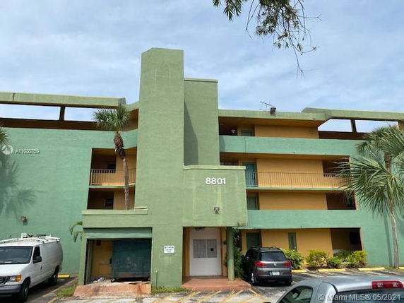 Front view of a multi-story residential building with balconies and green exterior.