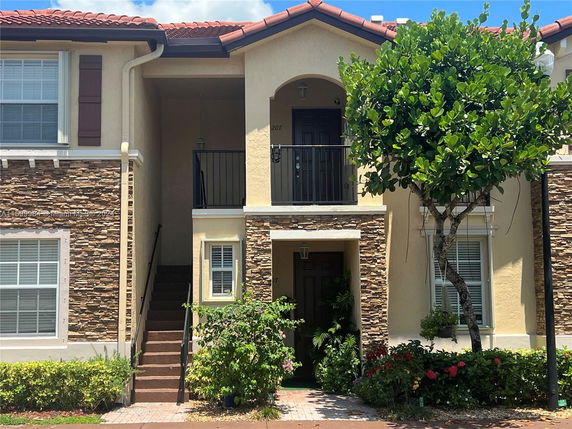 Front view of a two-story townhouse with a stone facade and a small balcony.
