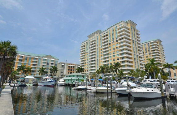 View of apartment buildings near a waterfront with boats docked in a marina.