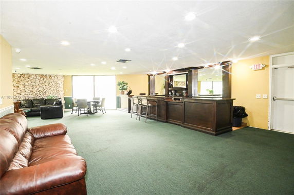 Interior view of a clubhouse area with a bar, seating, and lounge chairs.