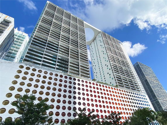 Front view of a tall modern building with circular window patterns at the base.