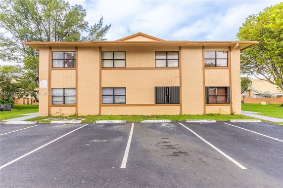 Front view of a two-story building with a parking area in front.