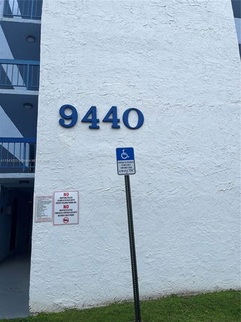 Front view of a building showing a wall with the number 9440 and a blue railing.