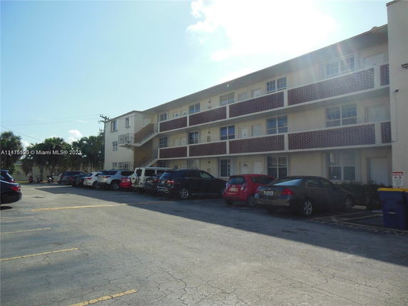 Front view of a three-story apartment building with parking area in front.