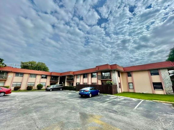 Front view of a two-story residential building with a parking area.