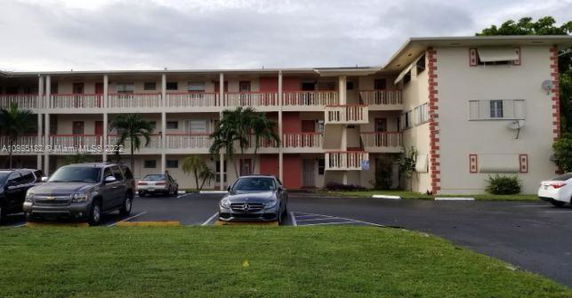 Front view of a three-story apartment building with a parking area in front.