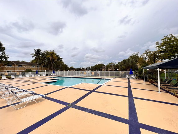 Outdoor swimming pool area with lounge chairs and umbrellas.