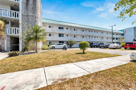 Front view of a multi-story building with balconies and parking area.