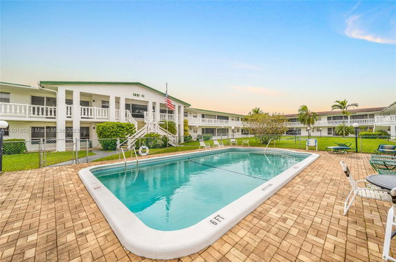 Outdoor swimming pool with surrounding two-story building.