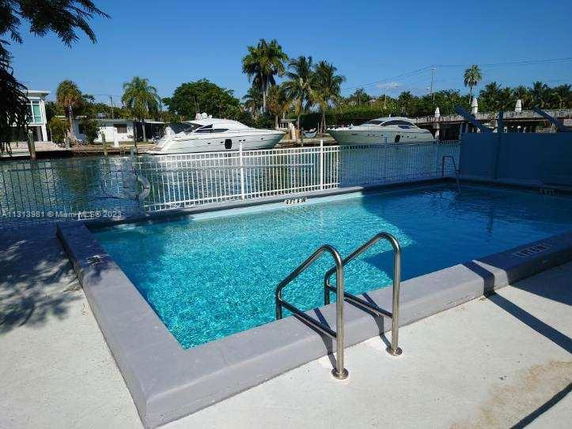 Swimming pool with a view of boats on the waterway in the background.