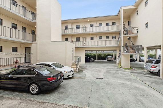 Outdoor parking area with multiple cars near an apartment building.