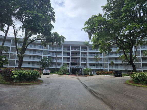 Front view of a multi-story residential building with balconies and a driveway.
