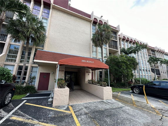 Front view of a multi-story building with a covered entrance and parking area.