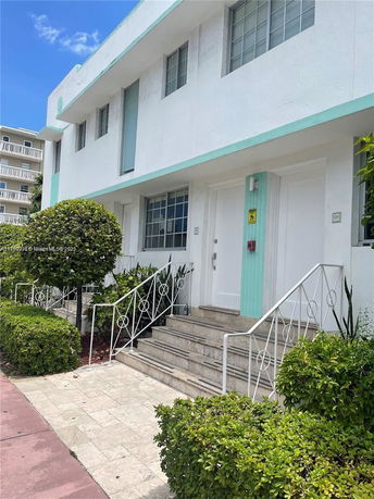 Front view of a two-story building with decorative iron railings and a light blue accent.
