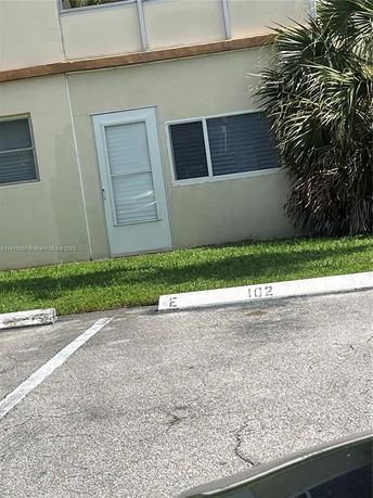 Outdoor parking area in front of a building with marked space and a nearby door.