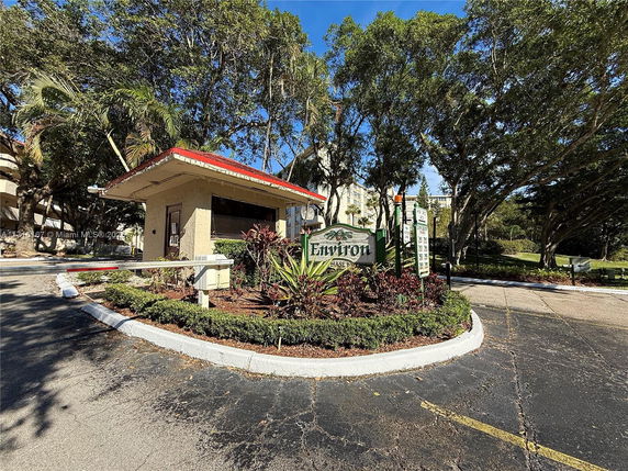 Front view of a small guardhouse with a red roof and surrounding foliage.