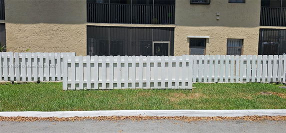 Front view of a building with a white picket fence.