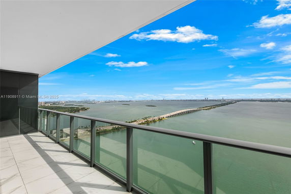 Panoramic view from a high-rise balcony overlooking water and cityscape in the distance.