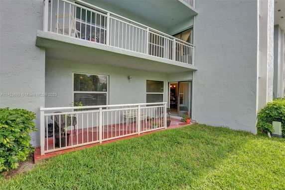 Front view of a building with a balcony and a small patio area.