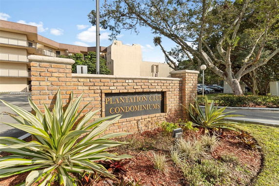 Front view of a multi-story condominium building with a brick entrance sign.