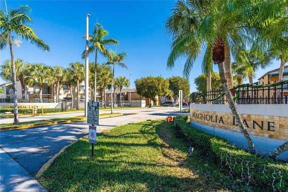Front view of a residential building with palm trees and signage.