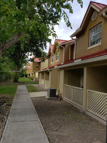 Front view of a townhouse complex with red roofs and beige walls.