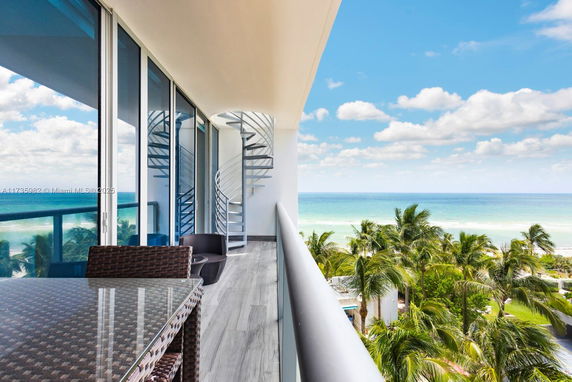 Balcony view looking out to the ocean with a spiral staircase and chairs.