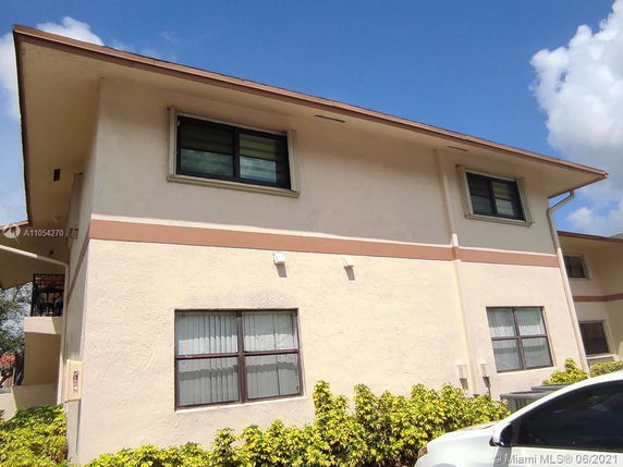 Front view of a two-story residential building with light-colored walls and multiple windows.