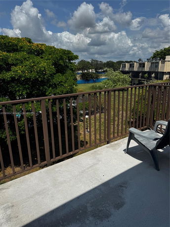 View of surrounding areas from a building balcony with railing and a chair.