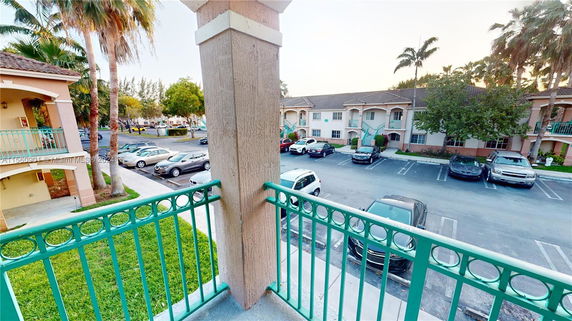 View from a balcony showing parking area and surrounding buildings.