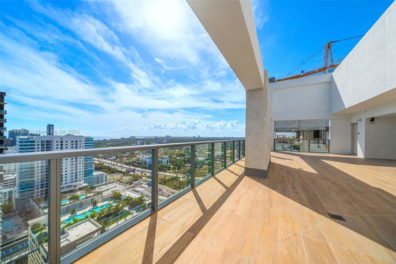 Rooftop area with glass railing offering a view of cityscape and clear sky.