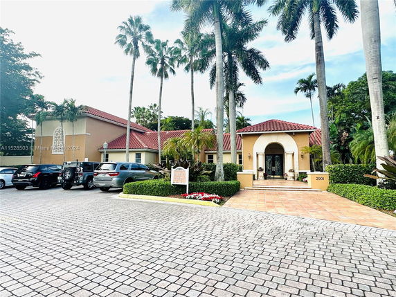 Front view of a house with a parking area and several parked cars.
