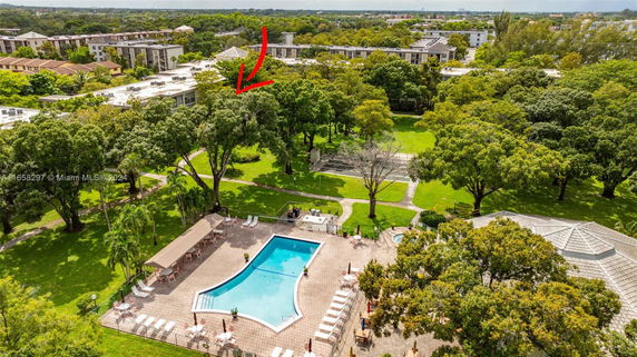 Aerial view of a swimming pool area with surrounding green spaces and trees.