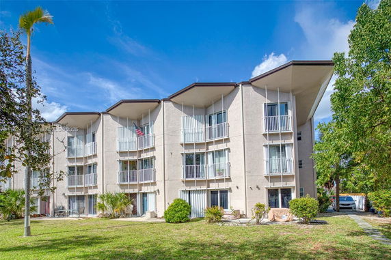 Front view of a multi-story building with balconies and a sloped roof.