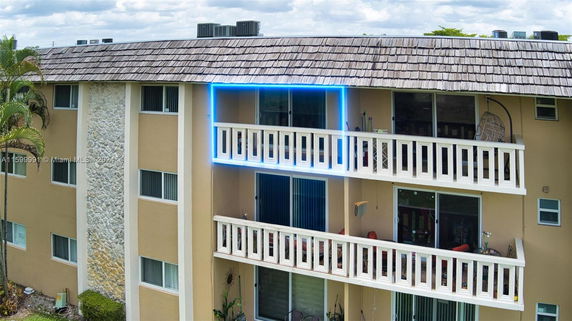 Front view of a multi-story building with balconies and a shingled roof.